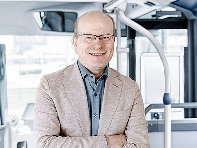 Doktor Oliver Mietzsch steht lächelnd im Bus